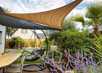 Voile d'ombrage à la couleur naturelle donnant un aspect chaleureux à une terrasse en bois